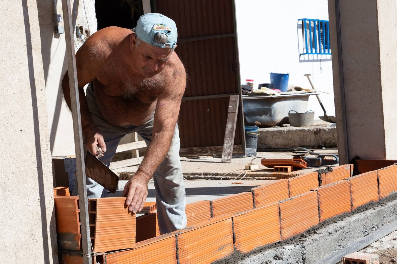 Un trabajador de la construcción labora sin camiseta debido a las altas temperaturas.