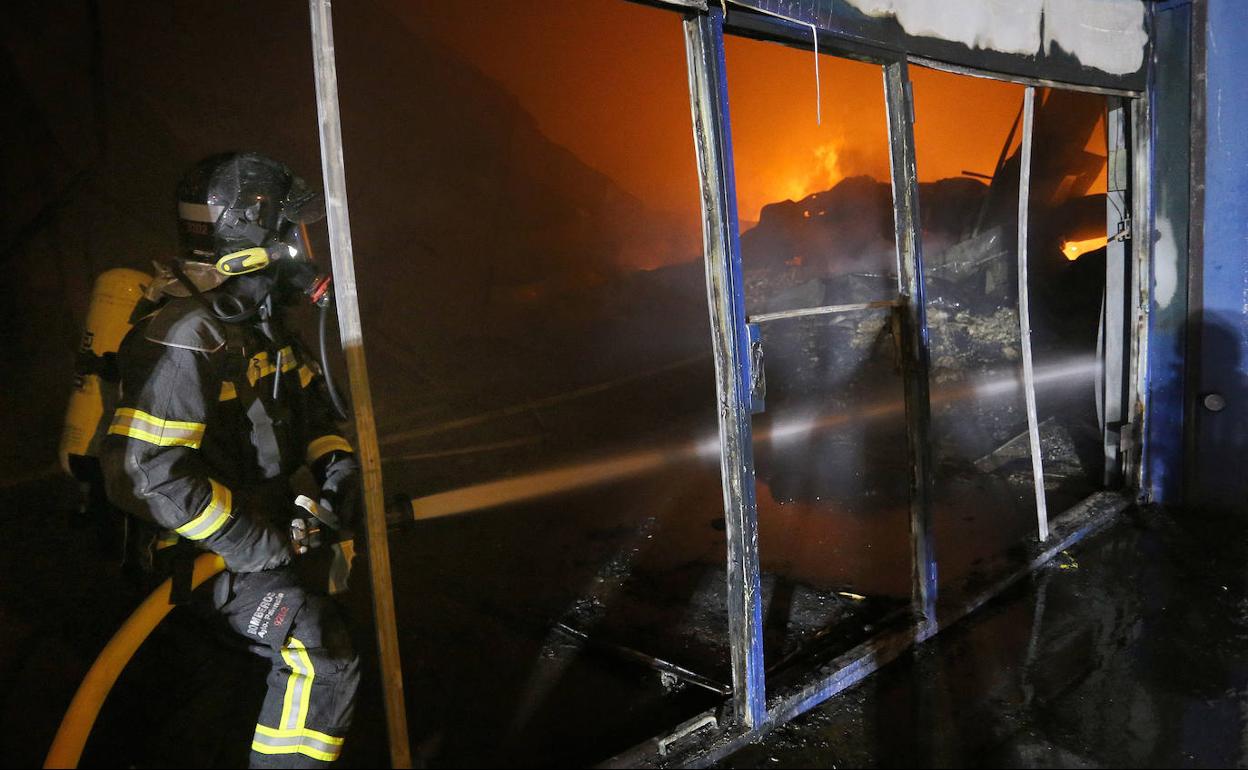 Un bombero sofoca las llamas en la nave incendiada. 