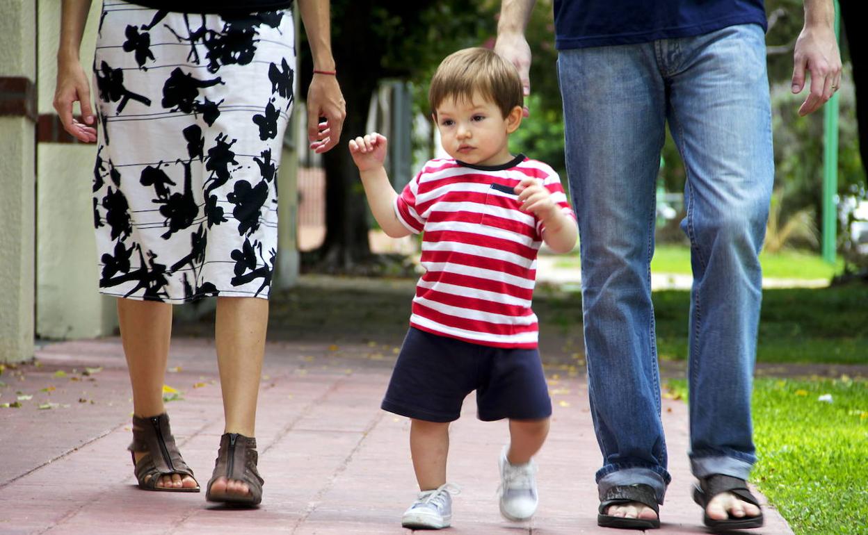 Un niño anda, acompañado de sus padres. 