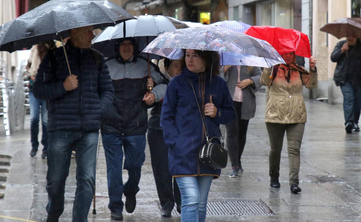 Varias personas caminan bajo la lluvia por la Calle Real de Segovia. 