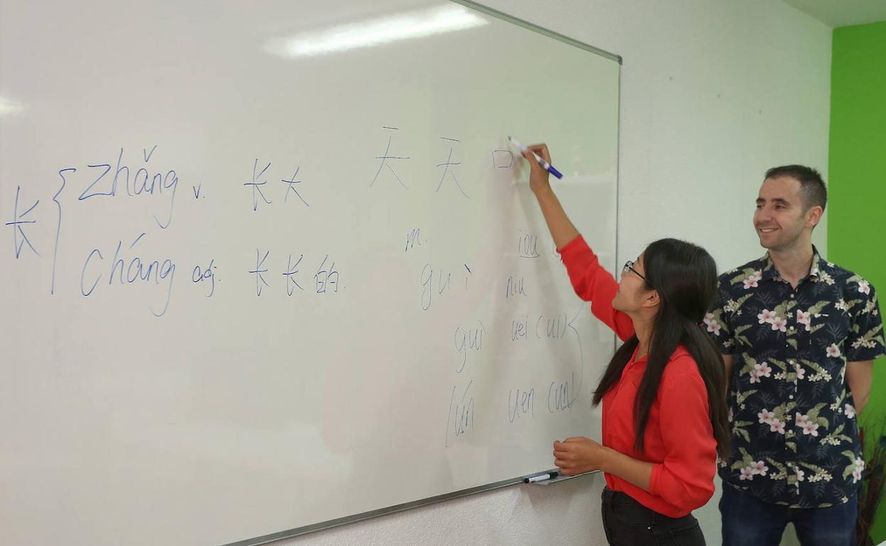 La profesora de la academia Tian Tian, Mengzi Yu, dibuja caracteres en la pizarra junto a su pareja, el salmantino afincado en Palencia Ángel Martín. 