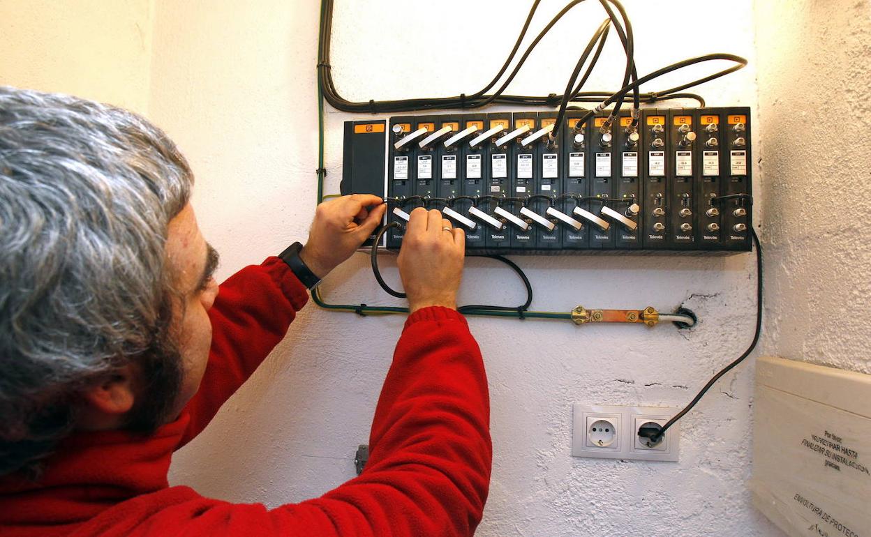 Un operario cambia la antena de un edificio.