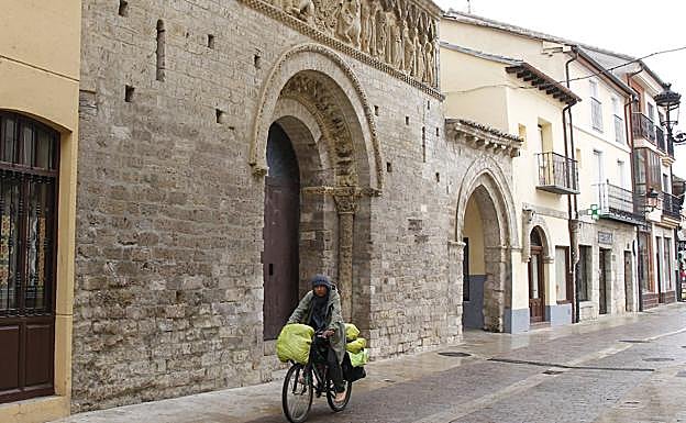 Un peregrino circula en bicicleta ayer frente a la Iglesia de Santiago en Carrión de los Condes.