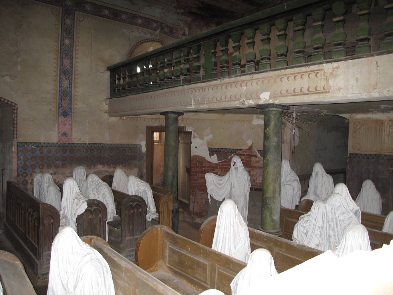Iglesia de San Jorge (Lukova, República Checa) | Fue construida en el siglo XIV, en torno al año 1352. En 1968, durante un funeral parte del techo se vino abajo y los residentes del lugar lo vieron como un mal presagio. Los rumores comenzaron a circular y pronto la iglesia alcanzó el estatus de maldita. Desde entonces, había permanecido cerrada hasta que en el 2014 Jakuv Hadrava convirtió su espacio en parte de su proyecto de tesis. El artista ideó una obra constituida por varias figuras fantasmales realizadas a tamaño natural que colocó aleatoriamente en la sala de oración como si fueran asistentes de una misa perpetua.