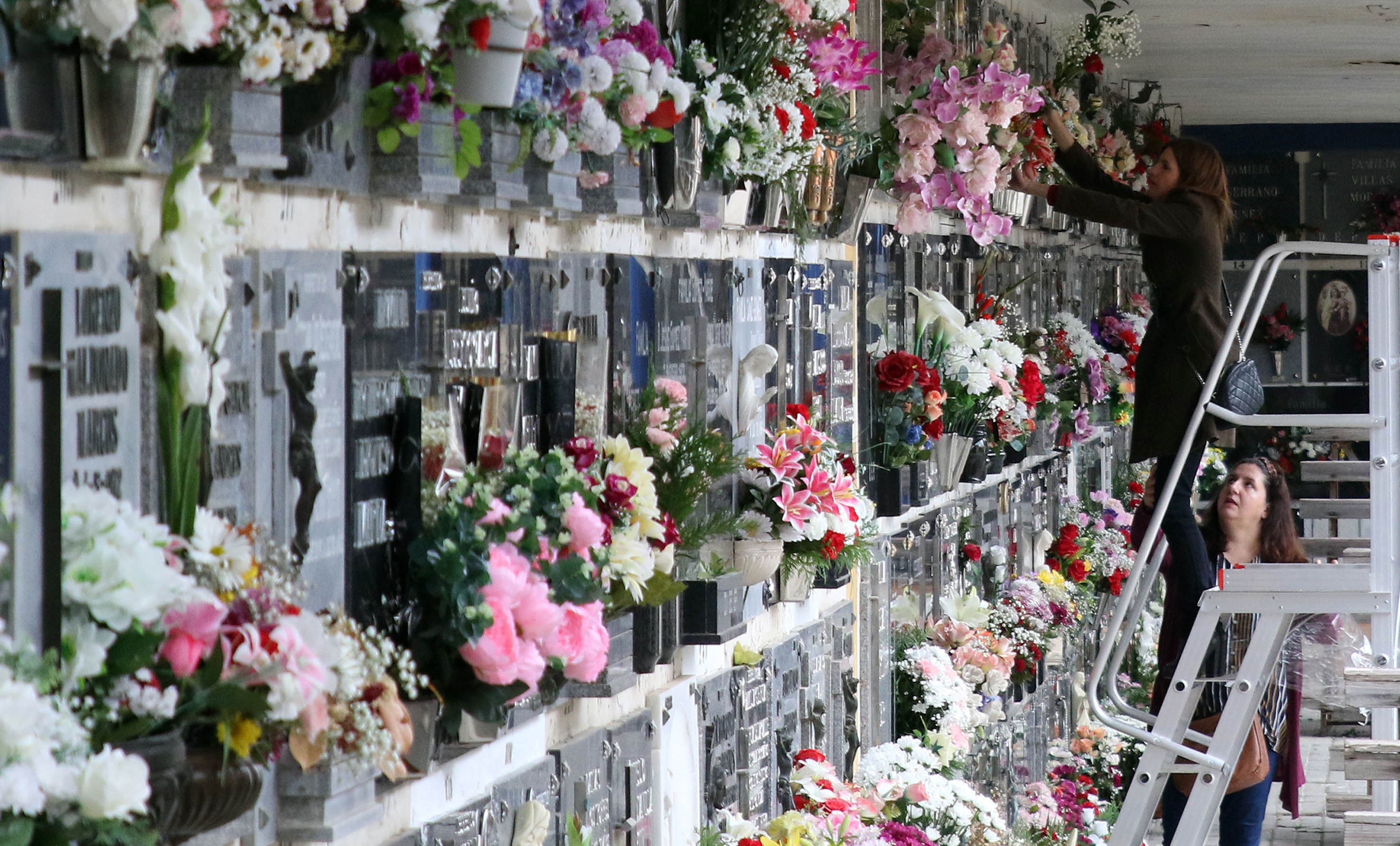 Dos mujeres colocan flores en un nicho, ayer, en el cementerio de Segovia. 