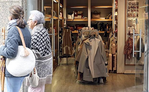 Dos mujeres pasan ante tienda de complementos y ropa.