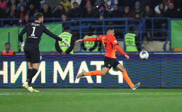 Heorhiy Bushchan intenta parar a Taison, del Shakhtar Donetsk, cuando golpea la pelota hacia aficionados del Dinamo Kiev