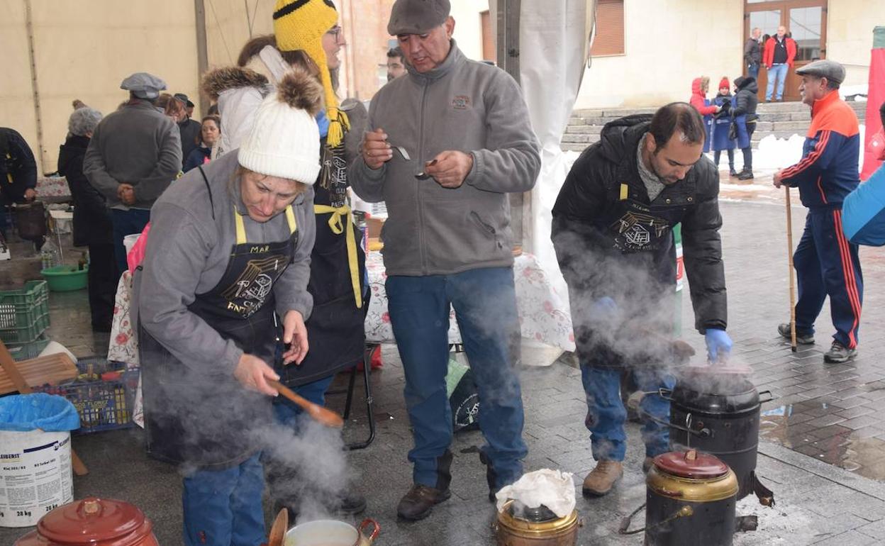 Los participantes se afanan en la preparación de las ollas bajo la carpa instalada. 