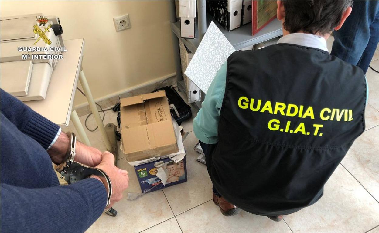 La Guardia Civil recoge documentos en presencia de uno de los detenidos.