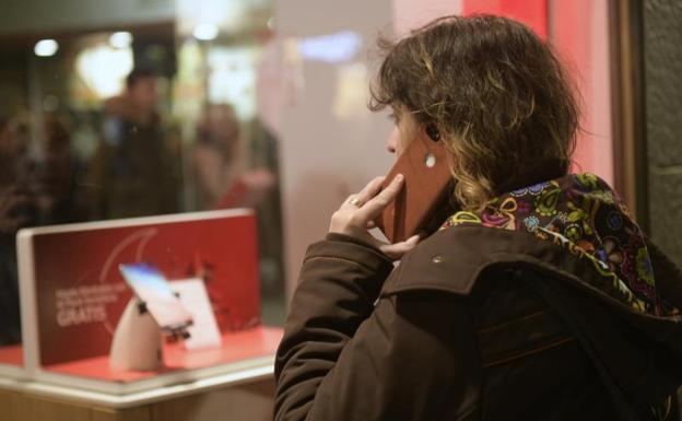 Una usuaria de telefonía móvil observa una terminal en un escaparate. 