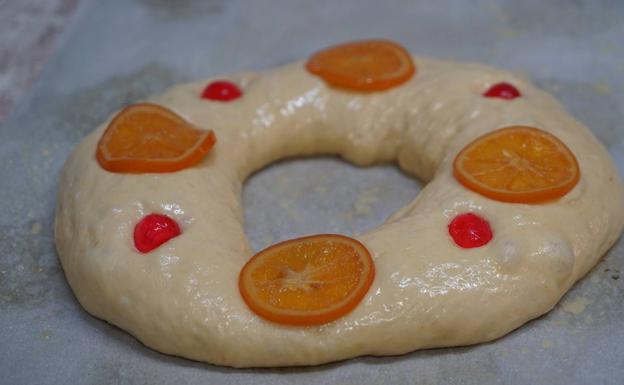 El roscón, pintado con huevo líquido y decorado con najanja y guindas. 