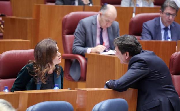 El consejero Carlos Fernández Cariedo conversa en el pleno de las Cortes con la portavoz de Ciudadanos, Ana Carlota Amigo.