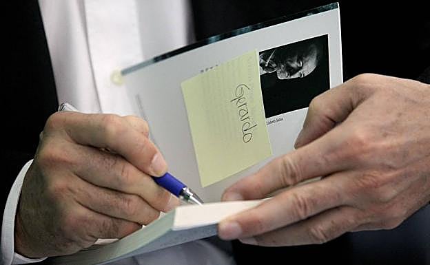 Arturo Pérez Reverte firma una dedicatoria en uno de sus libros.