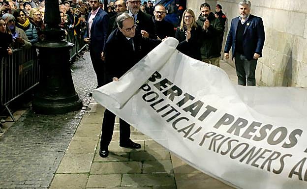 Quim Torra despliegua un cartel en apoyo a los presos políticos, bajo el balcón de la Generalitat.