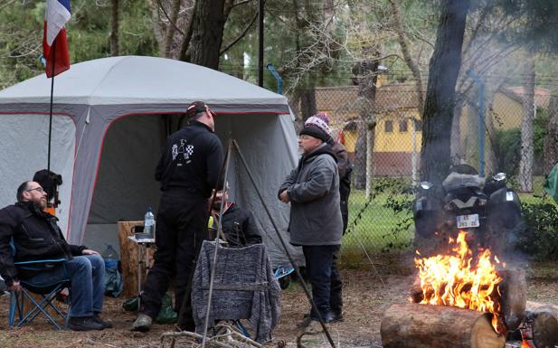 Imagen principal - Acampados en el recinto de El Hoyal, con las hogueras ya humeantes y las motos aparcadas y las viandas preparadas. 