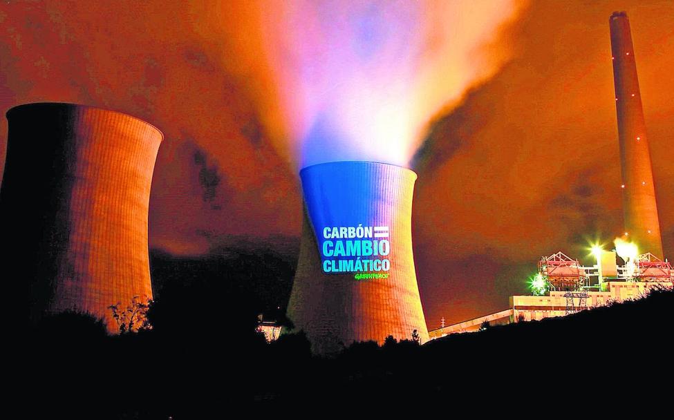 Un reflector de Greenpeace ilumina con un mensaje ecologista las torres de refrigeración de la central térmica de As Pontes.