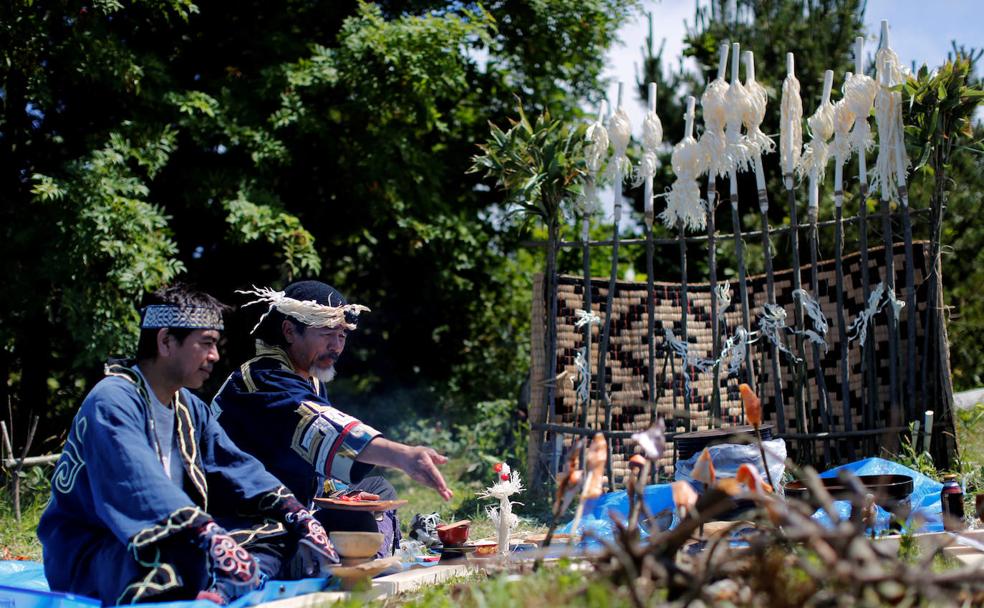 El artista ainu Koji Yukiy, su ayudante Fukumoto Shoji, sentados ante un altar que recuerda la derrota de su tribu frente a un ejército japonés en la batalla de Kaminokuni, en el siglo XV