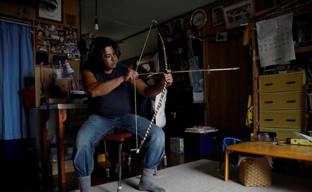 Un ainu examina un arco y una flecha, el arma que utilizan para cazar.