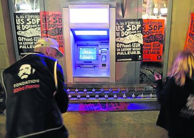 Imagen secundaria 1 - Las bancadas con reposabrazos, cada vez más habituales, impiden tumbarse. Activistas de la Fundación Abbe Pierre colocan carteles contrarios a la arquitectura hostil en la repisa de un cajero de París, donde se han colocado una hilera de puntas afiladas. Una persona sin hogar protesta por la incorporación de elementos punzantes en la entrada a una entidad bancaria en Inglaterra. 