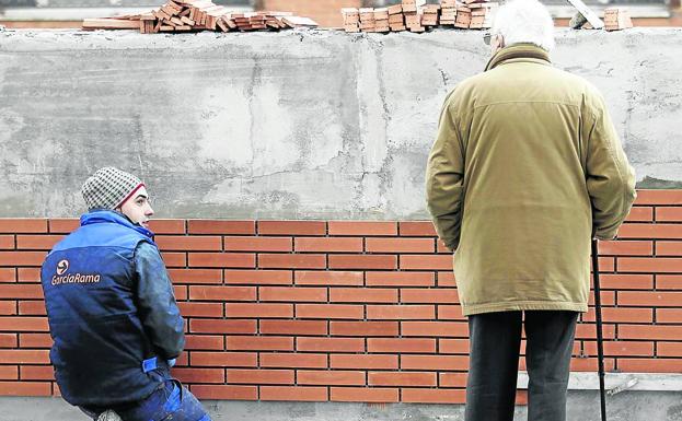 Un jubilado observa el trabajo de un albañil en una obra. 