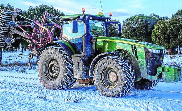 Un tractor parado ante una carretera nevada en las afueras de Ataquines.