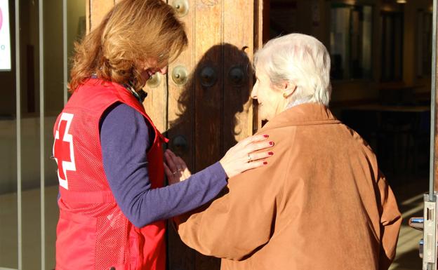 Una voluntaria acompaña a una mujer mayor a entrar en su casa. C