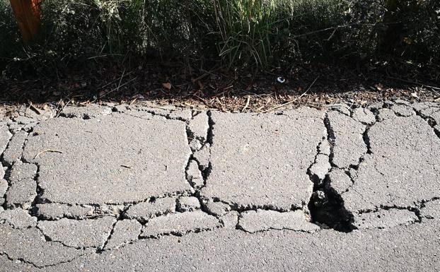 Imagen principal - Señales en la calle Arrabal. Arriba, detalle del bache y dos paseantes, este domingo, junto al lugar. 