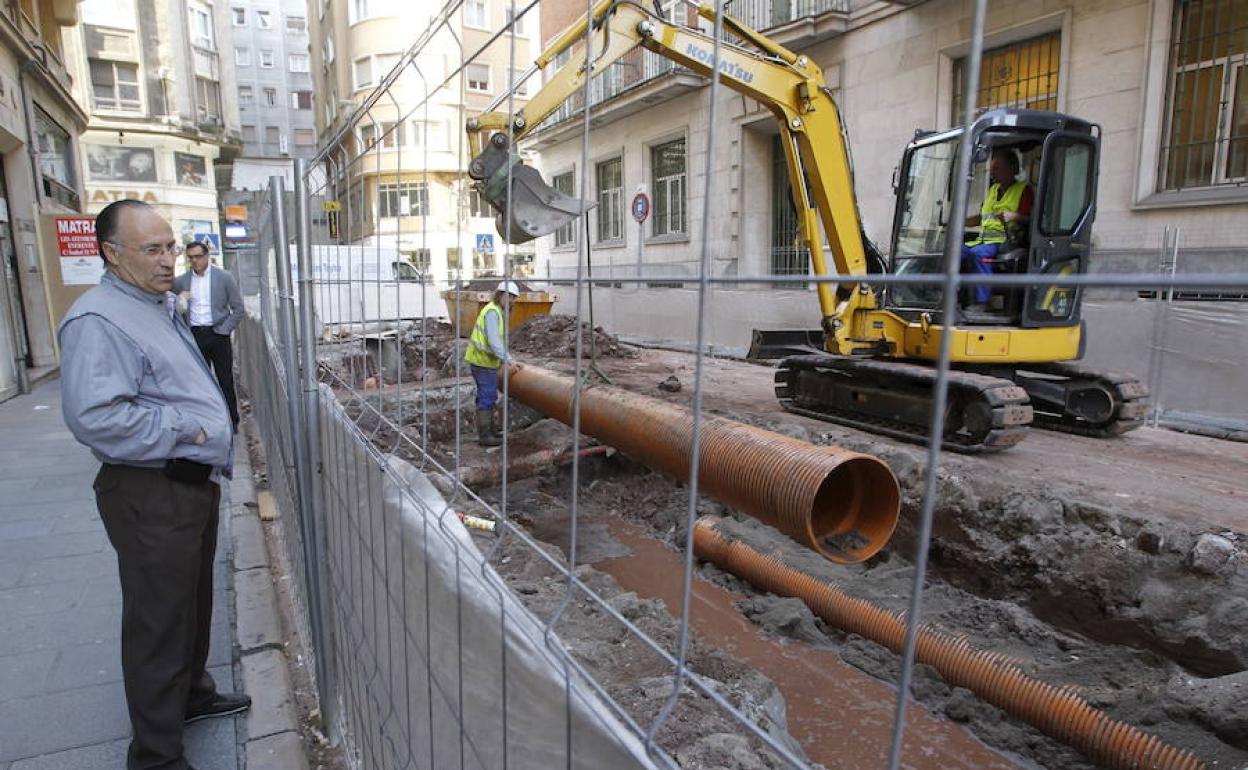 Un hombre observa a dos obreros que están trabajando.