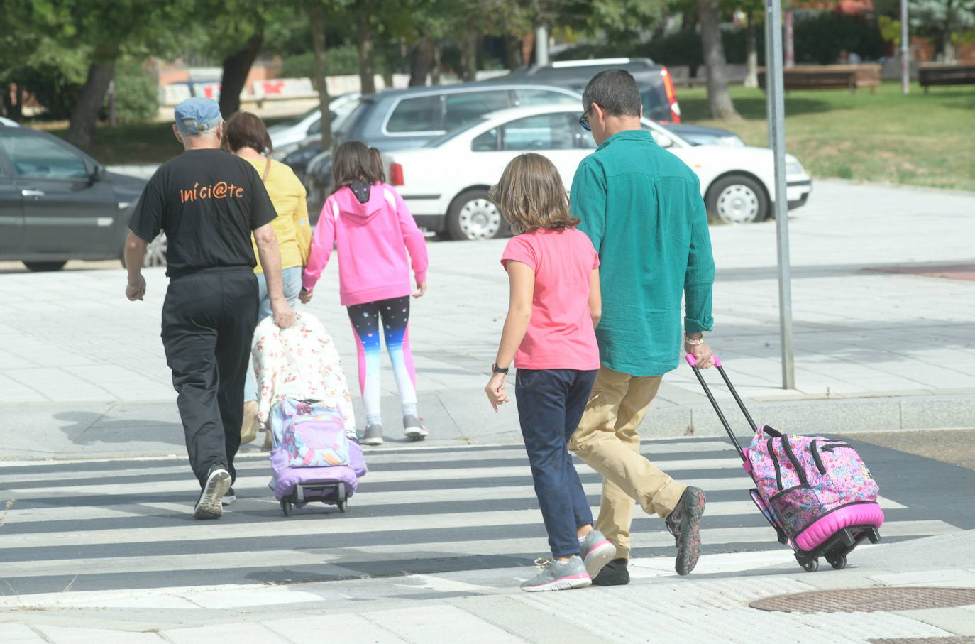 Niños cruzan la calle de la mano de sus familiares.