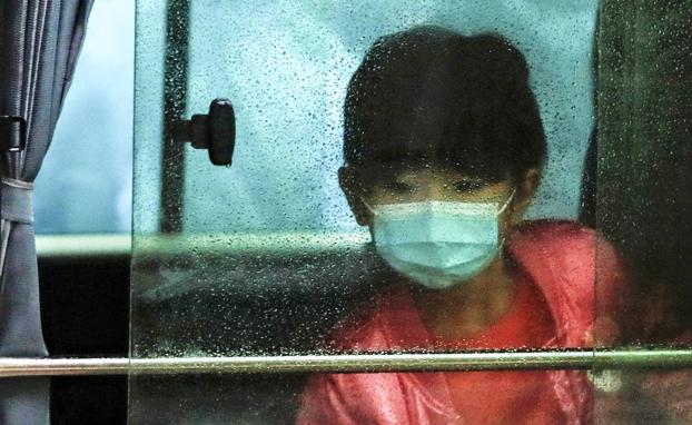 Una niña con mascarilla es evacuada en un autobús de un complejo residencial de Hong Kong.