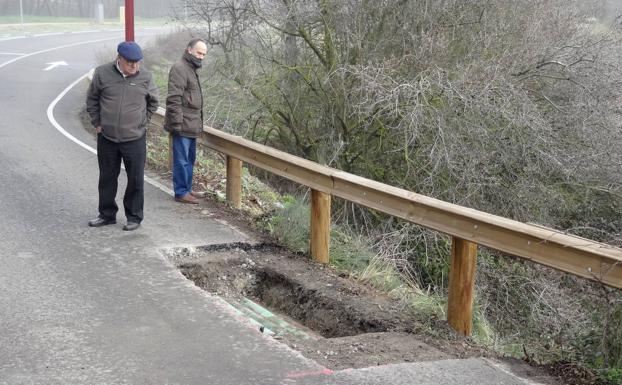 Dos vecinos contemplan la calzada abierta, en el puente de La Overuela. 