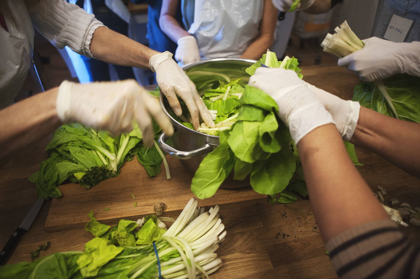 Un grupo de mujeres elabora un plato con acelgas. 