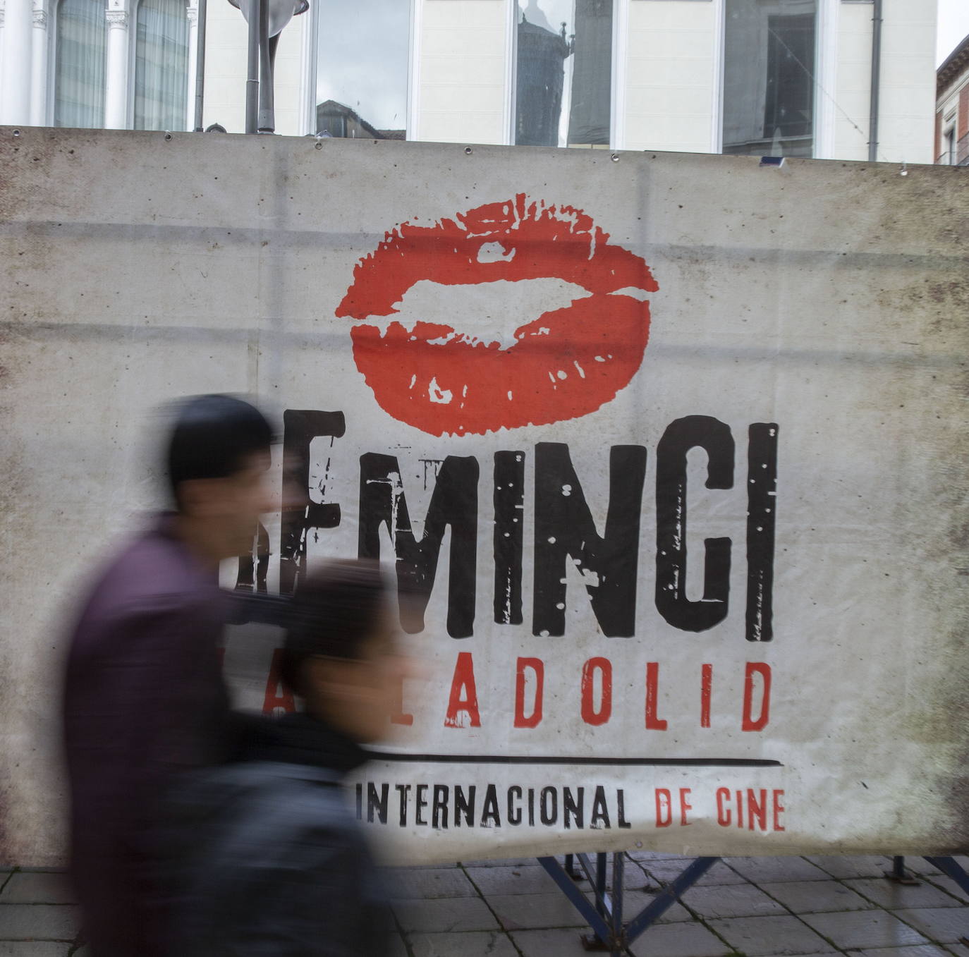 Dos personas pasan ante un cartel de la pasada edición de la Seminci, frente al Teatro Calderón.