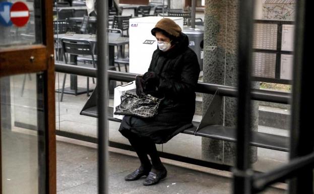 Una mujer espera el autobús en una parada en Milán.