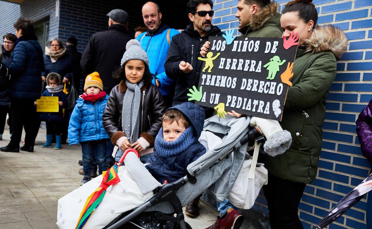 Una mujer sostiene una pancarta junto a unos niños. 