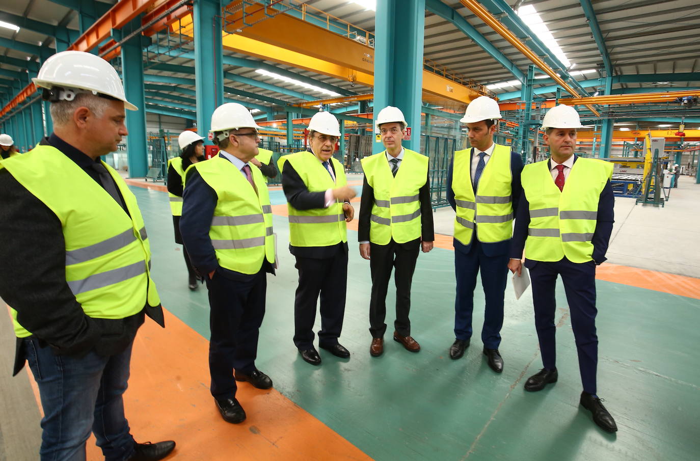 El consejero de Empleo e Industria, Germán Barrios (3D), junto al director general de Tvitec, Javier Prado (3I), durante la visita las instalaciones de la empresa en Cubillos del Sil (León).
