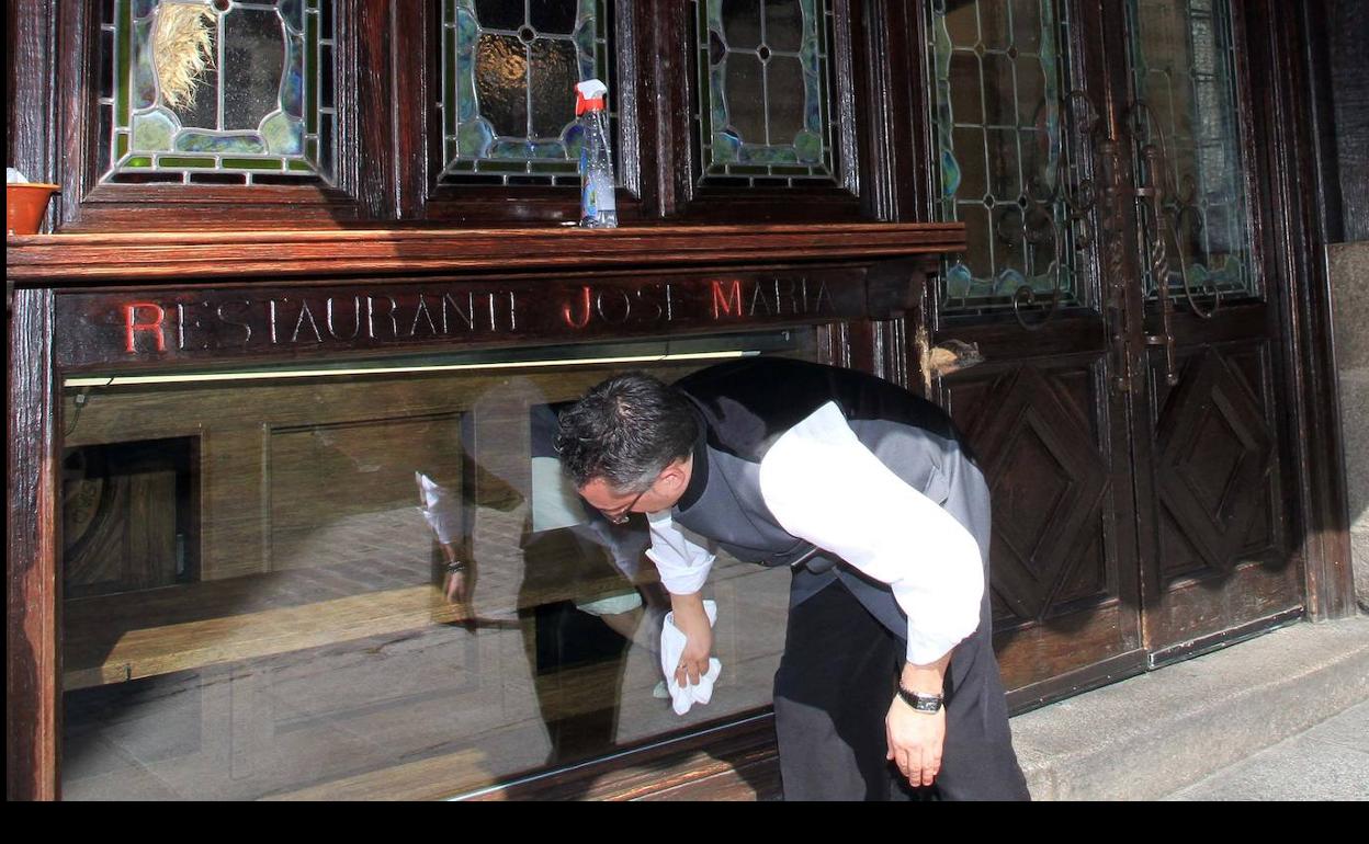 Un empleado del restaurante José María limpia la entrada del local. 