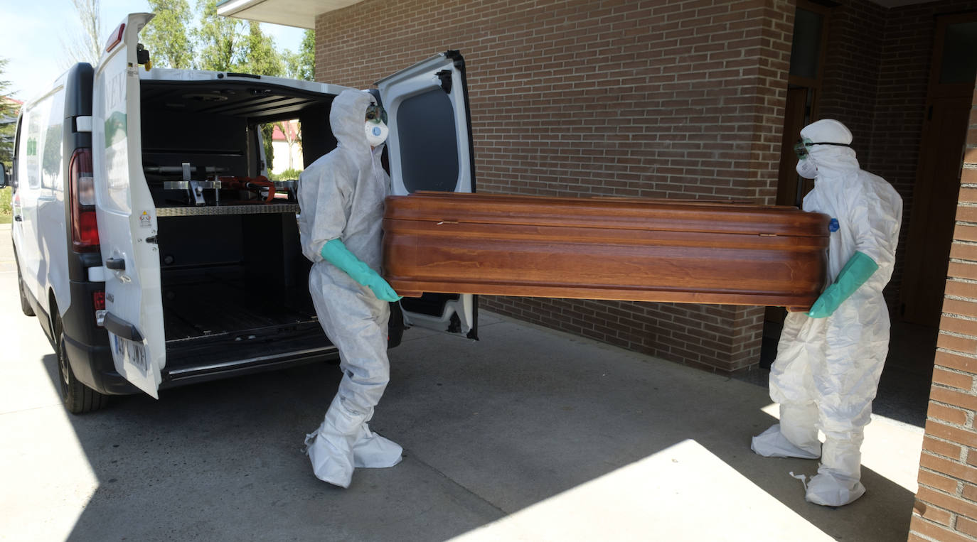 Empleados de la funeraria municipal de Valladolid Nevasa transportan un féretro.