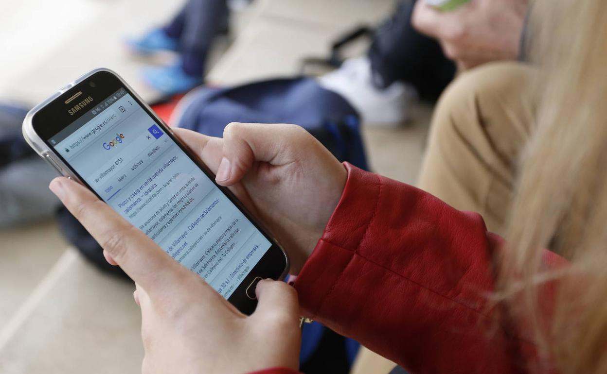 Una joven consulta su teléfono móvil.