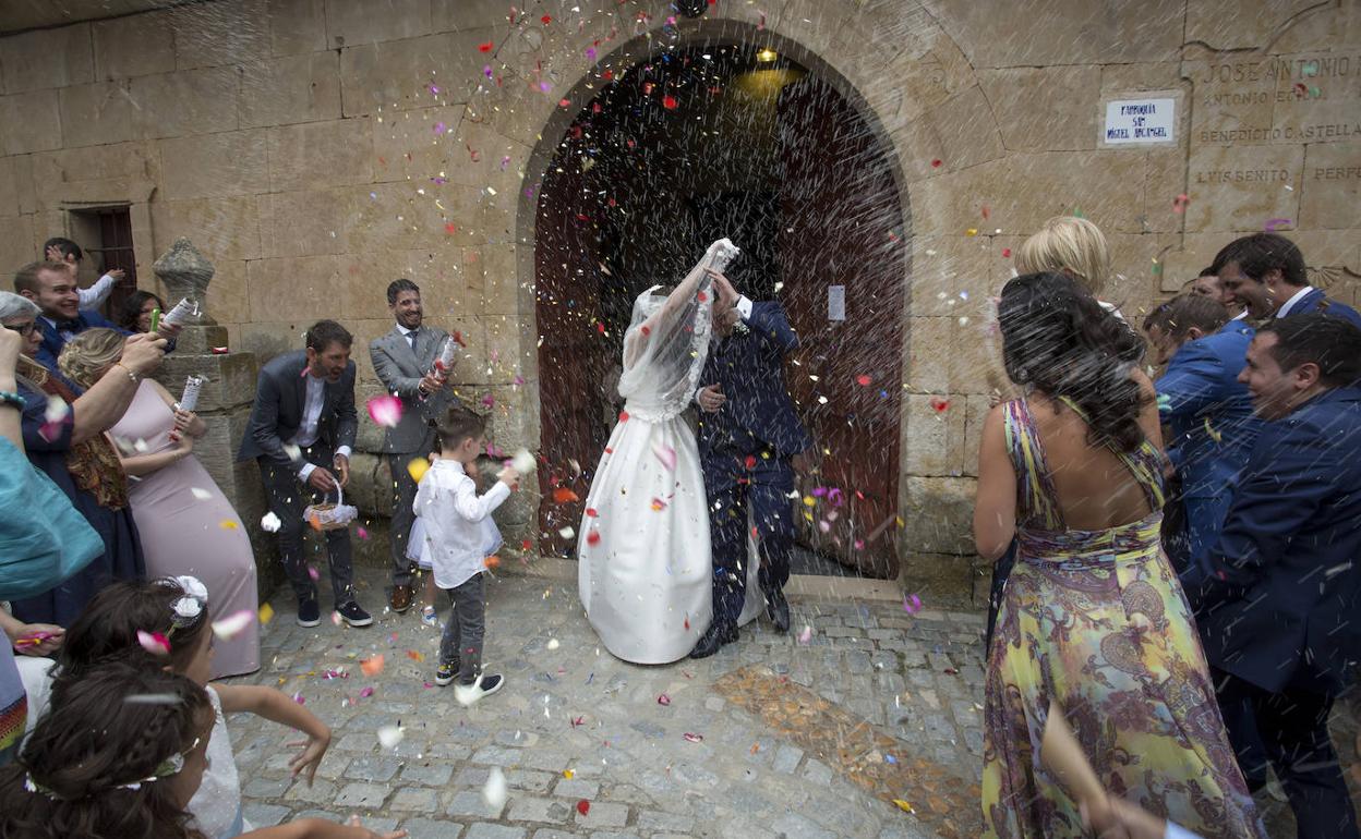 Una pareja de recién casados sale de una iglesia tras celebrar su enlace. 