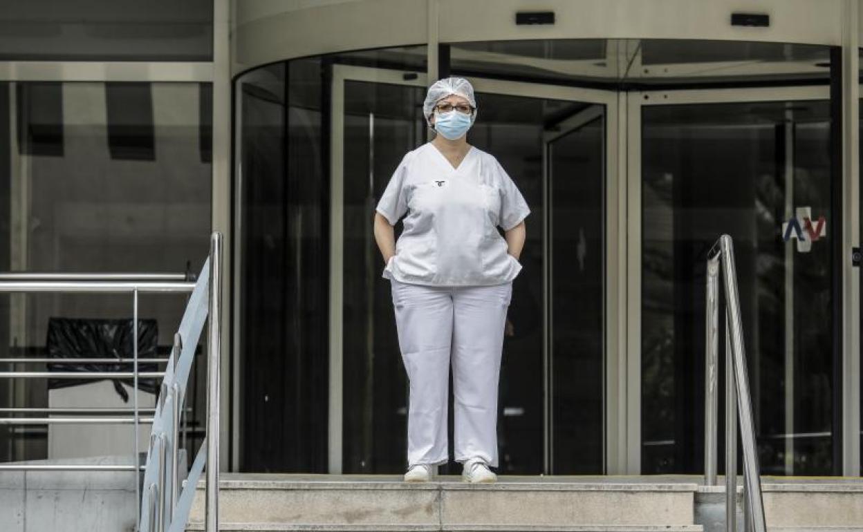 Sanitaria durante un minuto de silencio en la entrada del Hospital Doctor Peset, en Valencia. 