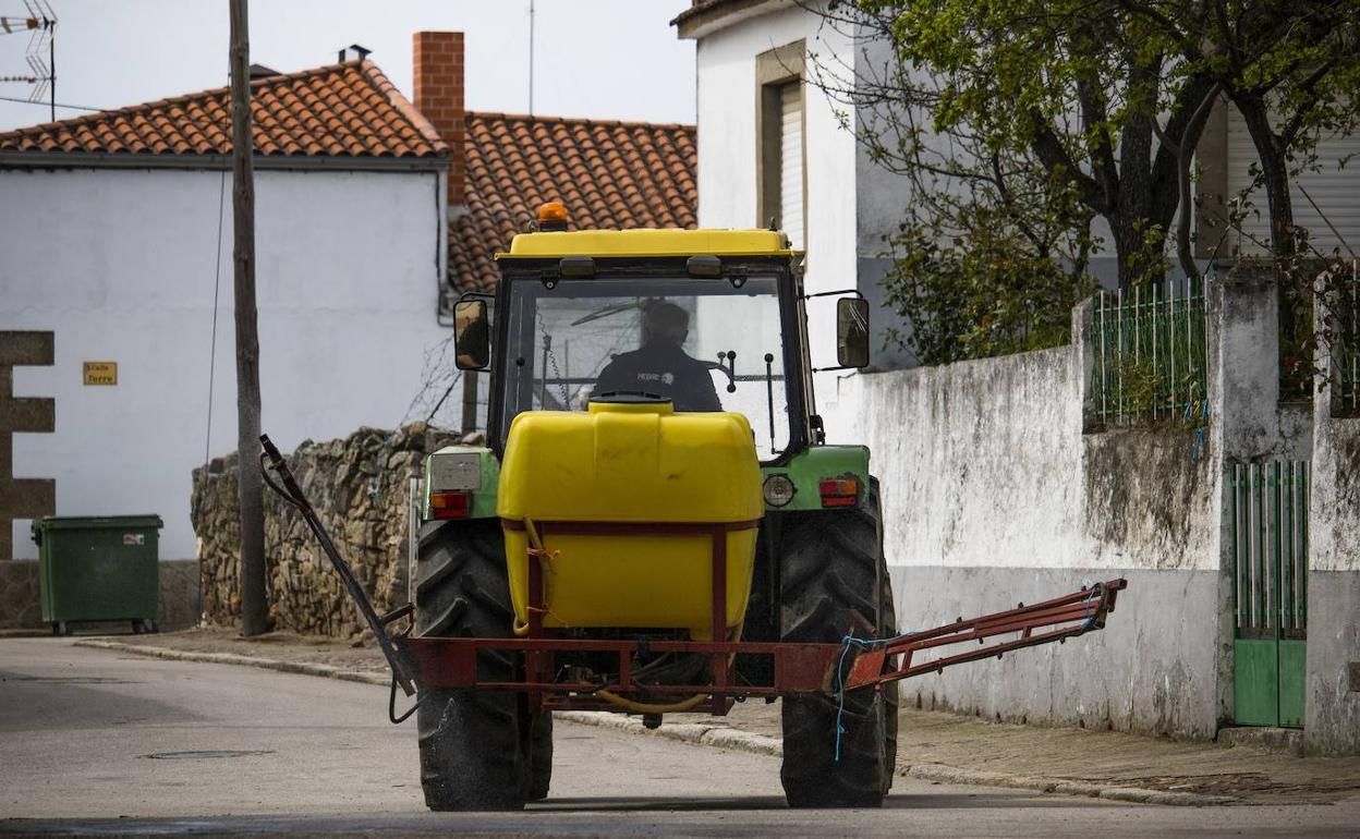 Un agricultor, con su tractor en un pueblo. 