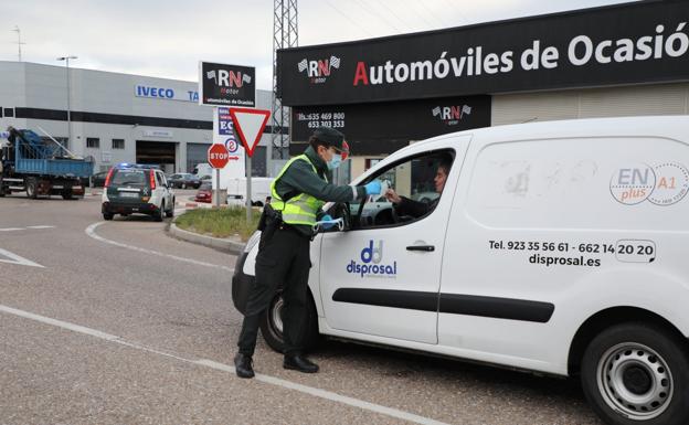 Un guardia civil entrega una mascarrilla a un trabajador en un polígono industrial de Salamanca.