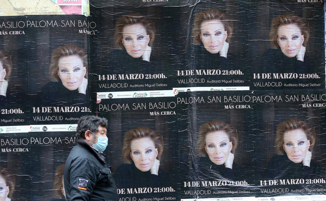 Un hombre con mascarilla pasa junto a carteles de la gira 'Más cerca', de Paloma San Basilio.