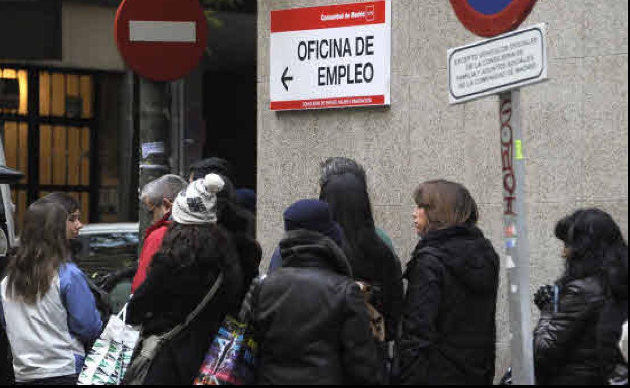 Un grupo de parados hace cola a las puertas de una oficina de empleo.