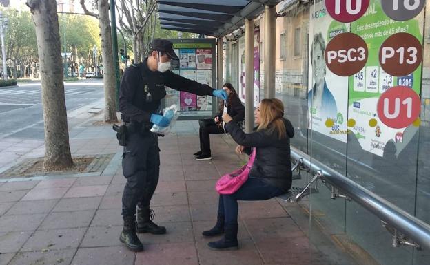 Un policía nacional entrega una mascarilla a una mujer en el Paseo Zorrilla.