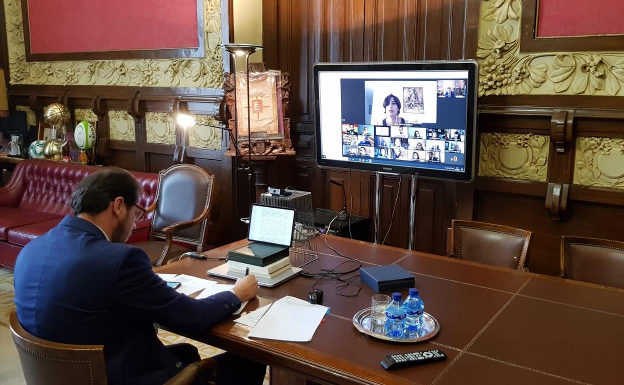 El alcalde de Valladolid, Óscar Puente, en su despacho en el Ayuntamiento, con la pantalla con la intervención de los distintos concejales de manera telemática. 