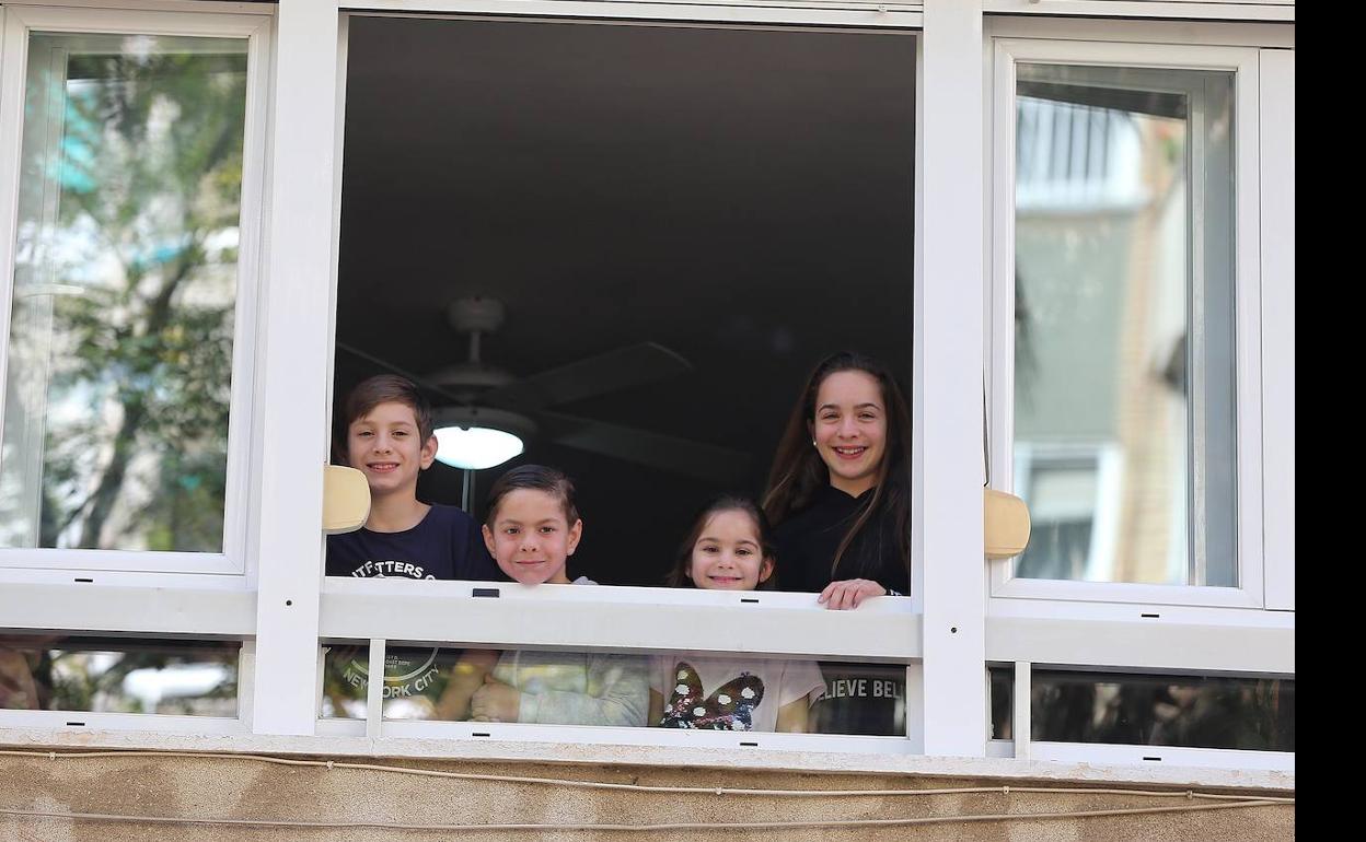 Cuatro hermanos de la familia Castillo Cobos asomados a la ventana de su hogar