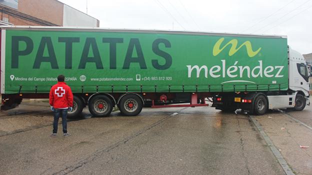 Un voluntario de Cruz Roja observa la maniobra de un camión de Patatas Meléndez. 