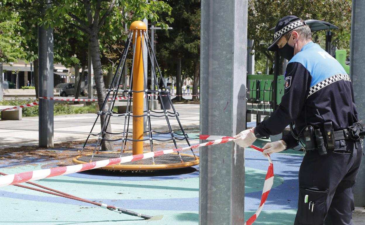 Un policía local recoloca la cinta del precinto de la zona de juegos del Salón.